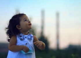 Little, young girl looking to the sky with power lines in the background.